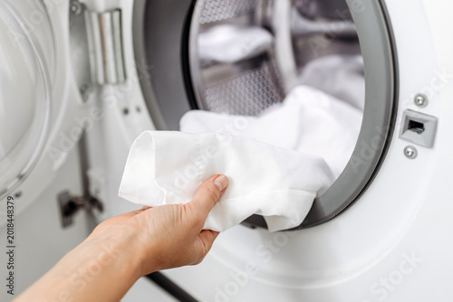 Canvas Print Hand reaching into front-loading washing machine to remove freshly washed white