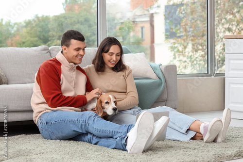 Young couple with cute Beagle dog at home