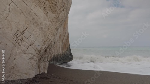 Rocky beach and sea waves under cloudy sky on a misty morning