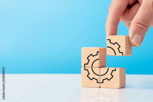 Hand placing final cube with gear icon for business automation