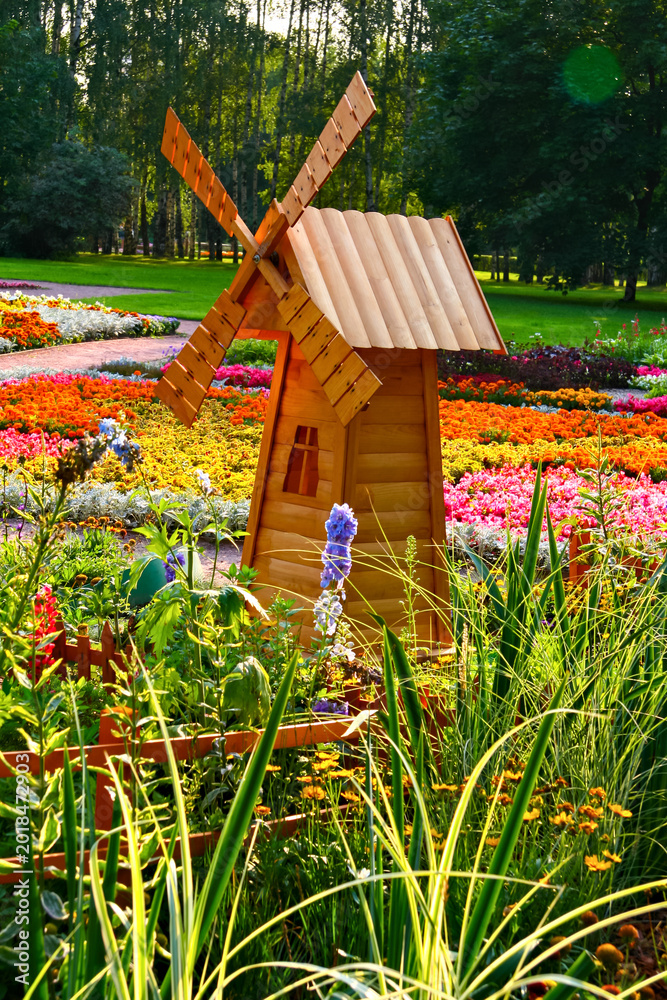 Obraz premium Wooden Windmill in Vibrant Flower Garden on a Sunny Day