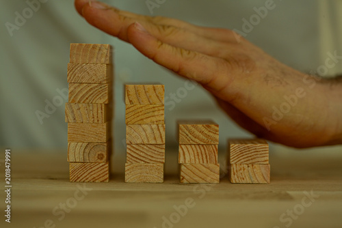 Foto A hand intervenes to stop the decline of a business graph made of wooden blocks