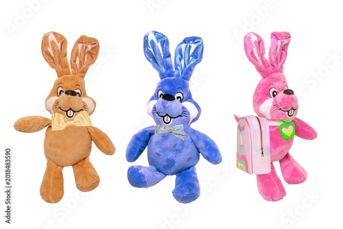 A collage set of three cute colorful plush bunnies with heart pendant, bow tie and bag isolated. Easter greeting card decoration item with space for design. Plush animal.