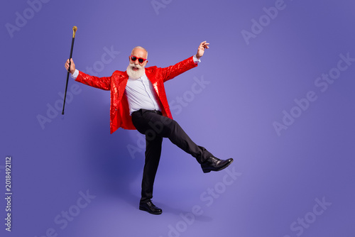 Cuadro en lienzo Energetic elderly showman in a red sequin jacket dances with baton in a vibrant