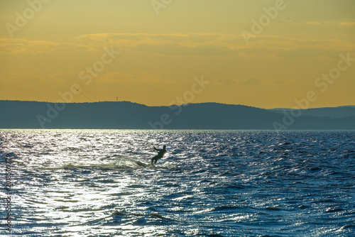 Fotografija kitesurfer on lake balaton gliding across sunlit water with warm sunset tones an