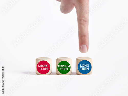 Hand pointing at long term wooden block in decision making