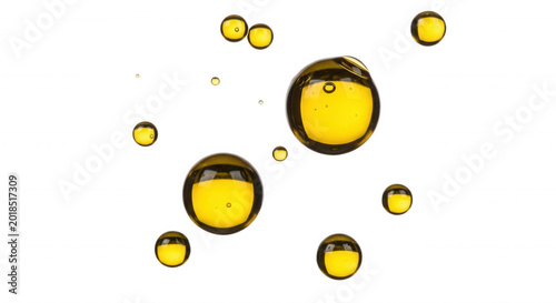 Floating yellow liquid spheres and bubbles isolated on a solid black background, macro of oil droplets in water