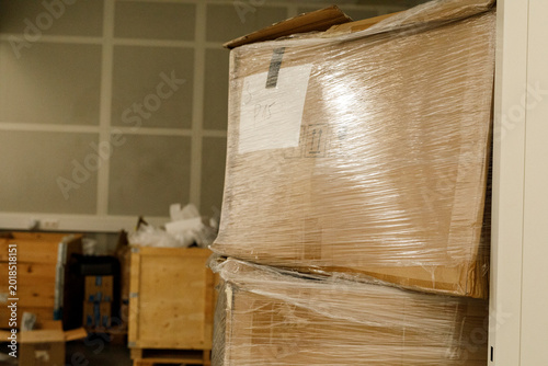 Cuadro en lienzo Cardboard packages are stacked and secured with shrink wrap in a storage facilit