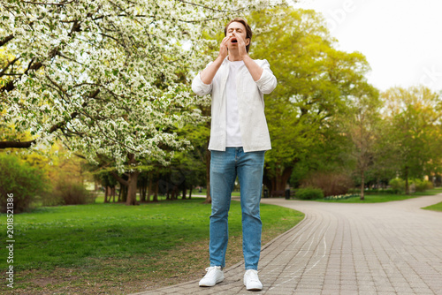 Konstfotografi A man stands in a blooming park covering his face as he prepares to sneeze