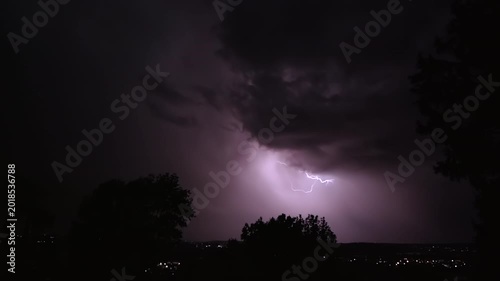 Lightning strikes on a dark night sky over a city landscape, captured in slow motion.