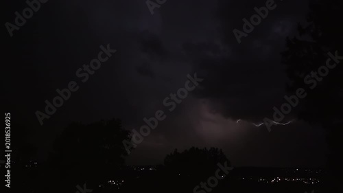 Lightning strikes on a dark night sky over a city landscape, captured in slow motion.