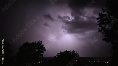 Lightning strikes on a dark night sky over a city landscape, captured in slow motion.