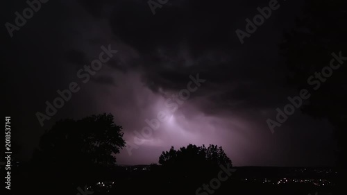 Lightning strikes on a dark night sky over a city landscape, captured in slow motion.