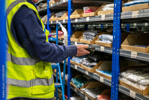 Tableau sur toile Logistics warehouse operative wearing a high-visibility yellow vest and using a