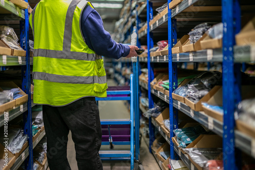 Foto Logistics warehouse operative wearing a high-visibility yellow vest and using a