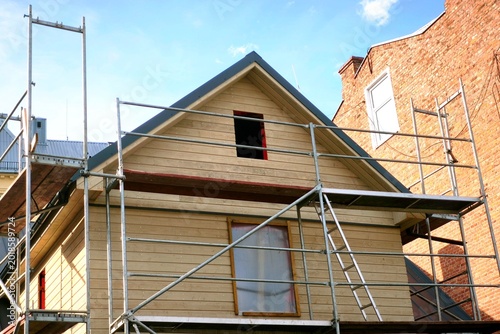 Photos Construction scaffolding set up against a wooden house for facade renovation