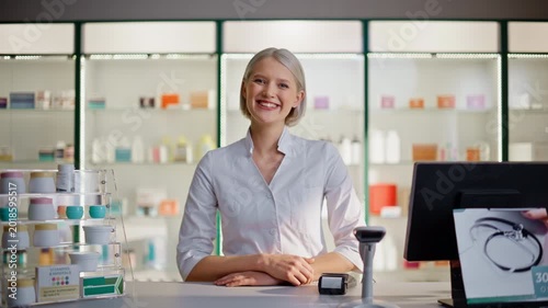 Pharma technician looking camera standing at prescription desk cashier portrait