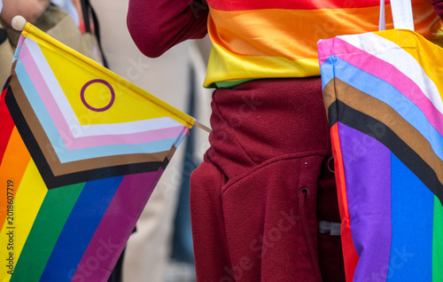 People celebrate LGBTQ pride with flags and colorful clothing in a public event at a city street