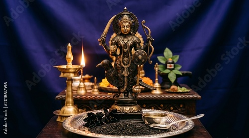 Intricate Bronze Statue of Lord Shani Dev Standing Against a Deep Indigo Silk Background, Representation of Shani Pradosh Vrat Rituals