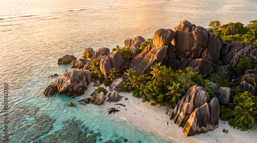 Idyllic tropical island paradise with granite boulders, palm trees, and turquoise water at sunset.