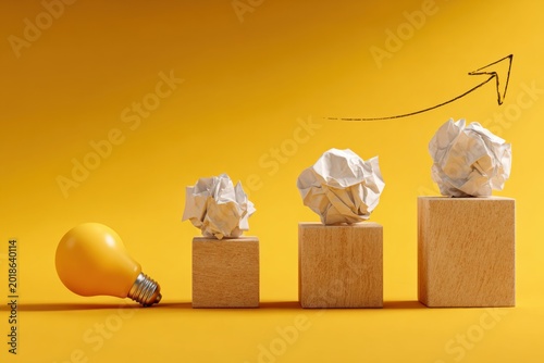 Concept of Business Growth and Idea Development Illustrated with Lightbulb and Crumpled Paper on Blocks.