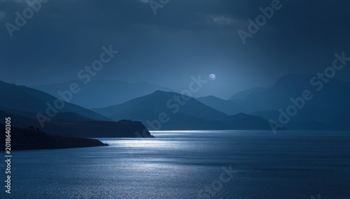 Serene Moonlight Reflecting on Calm Water with Mountain Silhouettes.