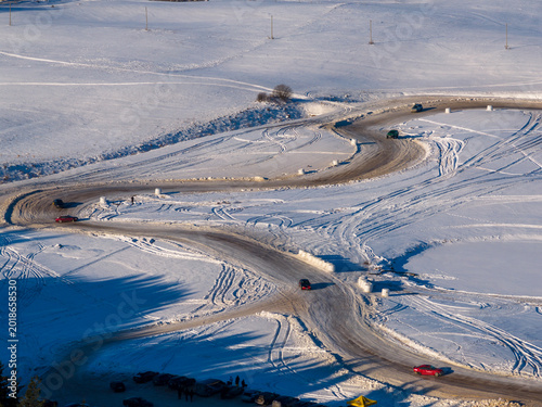 Aerial view of cars driving on a winding snow-covered track during a winter rally in Moletai, Utena County, Lithuania.