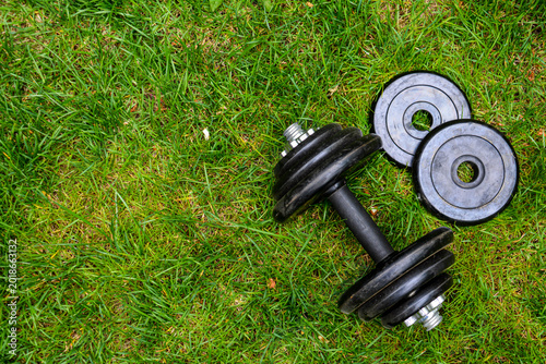 Dumbbells on green grass background. Fitness and healthy lifestyle concept. Fitness equipment on the grass. Bodybuilding