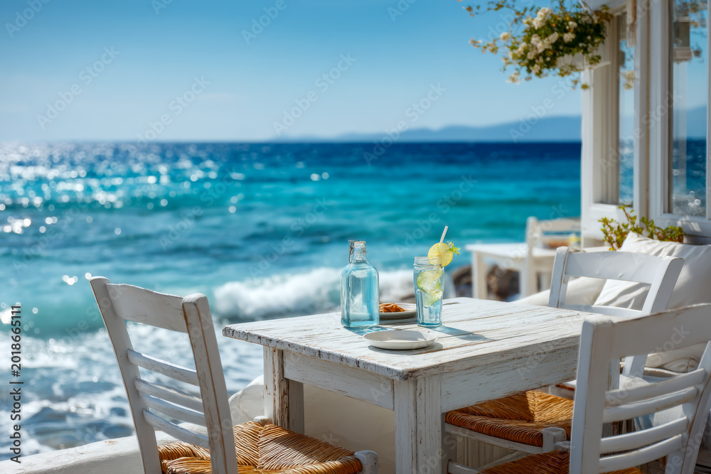 Obraz premium Idyllic summer setup with a white wooden table and refreshing drinks at a seaside cafe overlooking the sparkling turquoise sea