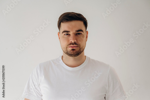 Tableau sur toile Male model with short brown hair and beard wearing a plain white t-shirt poses a