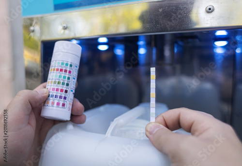 Quadro su tela Man checking water quality at a public vending machine using a test strip