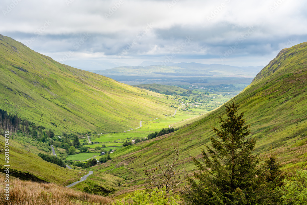 Fototapeta premium Glengesh Pass winding through a green mountain valley in County Donegal, Ireland. A scenic road landscape of the Wild Atlantic Way and remote Irish highlands.