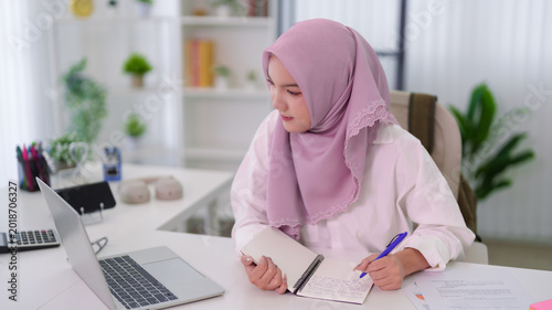 Fotografie Muslim women student wearing hijab studying online education business course wri