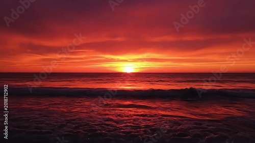Fiery ocean sunset paints the sky with vibrant hues and calm waves.