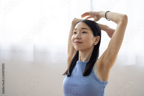 Free Download Asian Woman Stretching and Relaxing by a Bright Window - GFXLoad