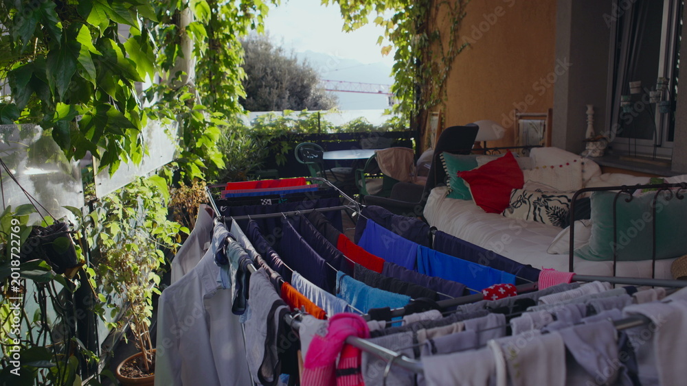 Fototapeta premium Laundry Hanging on Terrace with Plants Furniture and Distant Lake View Creating Peaceful Domestic Scene of Fresh Air Routine and Outdoor Home Living