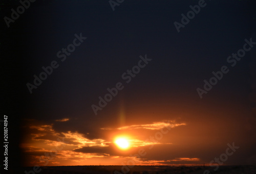 The sun sets behind dark clouds in the late evening. Background
