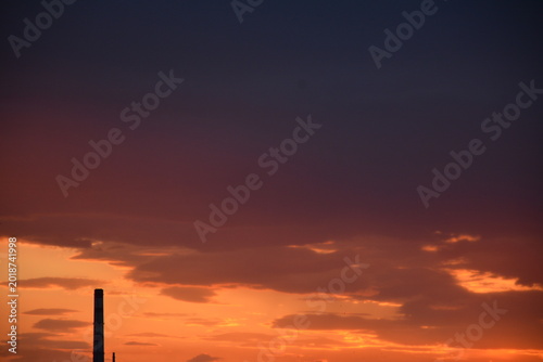 Dark red sky in the late evening. An industrial chimney on the horizon