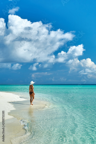 Paradise beaches of the Maldives. Tourism, travel and vacation in a luxury resort. Woman in bikini on the background of the sea and the beach
