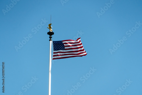 American flag waving on a flagpole against clear blue sky. Patriotic symbol of the United States during national remembrance and Memorial Day