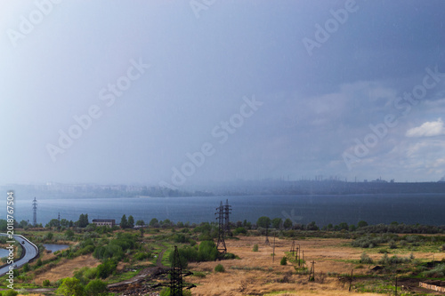 Rainstorm over lake and industrial cityscape