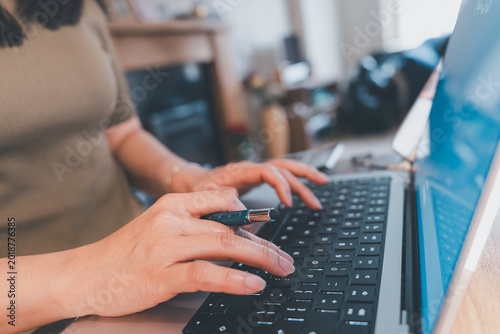 Woman working on laptop keyboard at home office, checking email, online shopping, customer service, sales, meeting, and studying with modern remote work lifestyle concept.