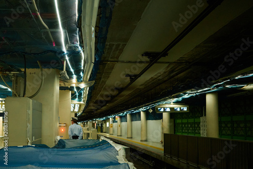 Renovation work at a subway station platform in Tokyo, Japan, construction site with blue protective sheets and exposed ceiling structure in underground terminal