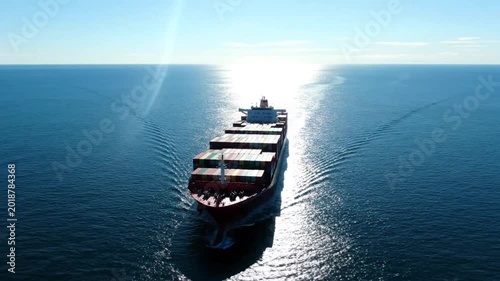 Large cargo ship sailing across the ocean on a bright sunny day carrying shipping containers