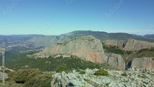 Drone shot flying backwards reveals a person hiking on the rocky Ponoig (1,181 m.) mountain ridge with a stunning panoramic view of the Costa Blanca mountain range in Alicante - stock video
