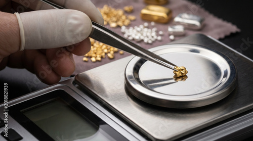 Jeweler weighing gold pieces with tweezers on digital scale  