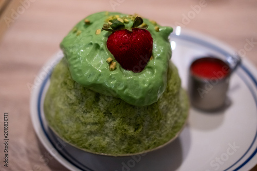 Matcha, green tea shaved ice with strawberry on top, served in a bowl
