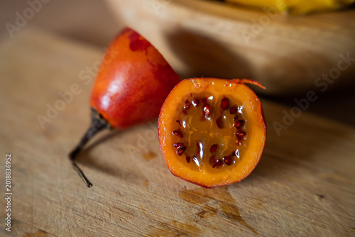 фотографія A fresh tamarillo fruit is cut in half on a wooden cutting board