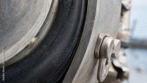 watertight. Close-up of a thick rubber seal compressed against a steel ship's hatch. mobility guides, transit brochures, designed for mobility and urban transit guides, supports logistics messaging.