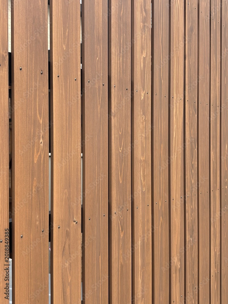 Fototapeta premium Vertical wooden slat fence with natural brown grain pattern and screws